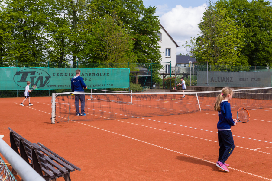 Zwei Girls besteigen den Trainer am deutschen Tennisplatz